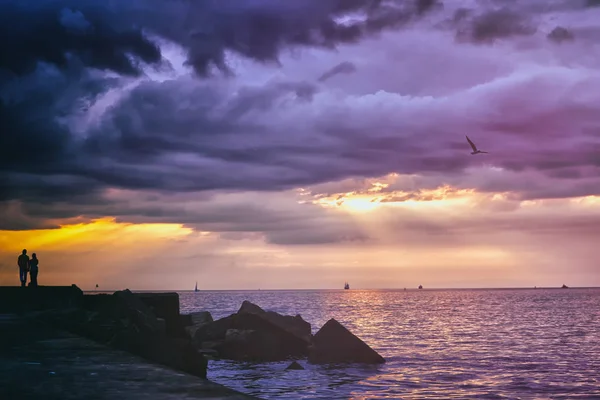 Paar spaziert bei Sonnenuntergang am Meer Stockbild