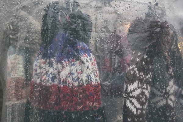 Knitted woolen hats under the film with drops — Stock Photo, Image