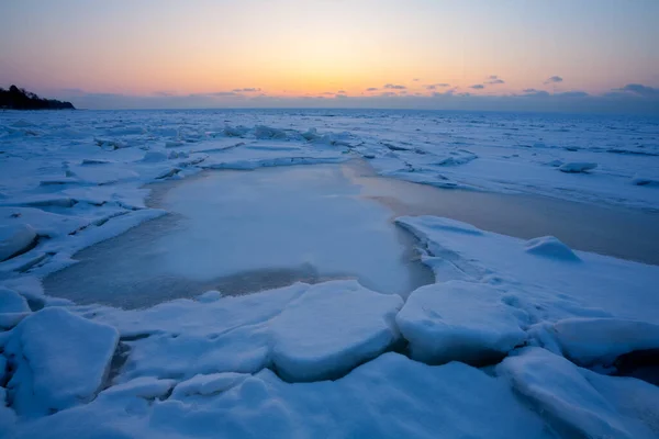 Sunset in the orange sky over the blue ice of the Baltic Sea — Stock Photo, Image