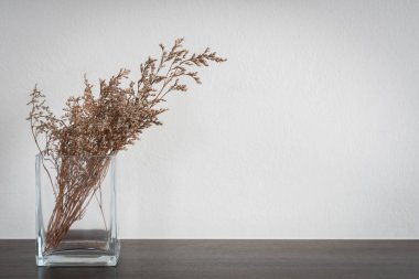 Kuru Limonium Caspia ahşap masa üzerinde cam vazoda