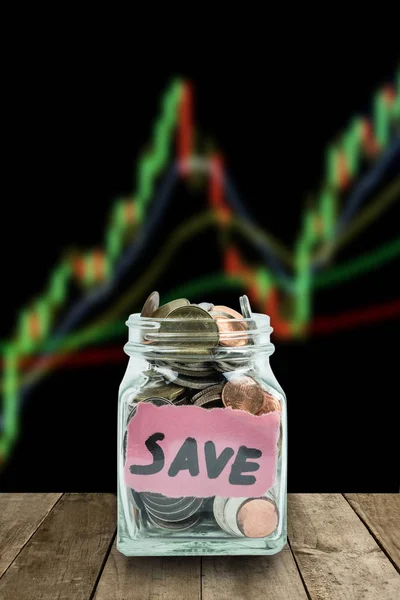 Glass jar of coin with graph of stock market in background — Stock Photo, Image