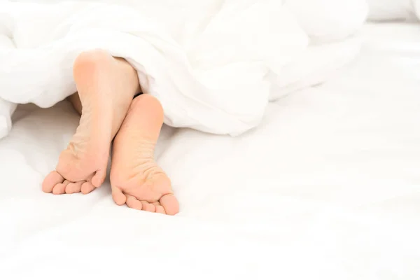 Füße im Bettbezug mit Decke — Stockfoto