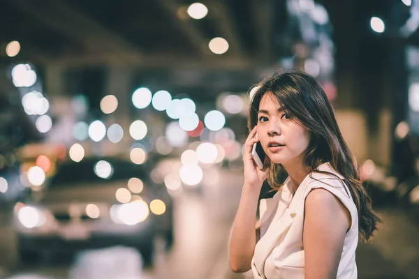 Азиатка разговаривает со смартфоном по ночам — стоковое фото