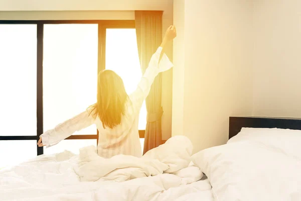 Rückansicht einer Frau, die sich nach dem Aufwachen im Bett dehnt — Stockfoto