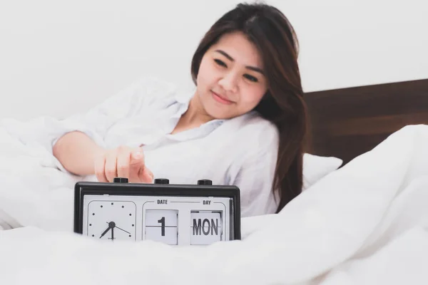 Счастливая азиатка останавливает будильник в постели — стоковое фото