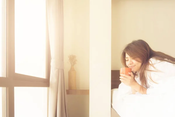 Азиатка улыбается, когда пьет кофе по утрам — стоковое фото