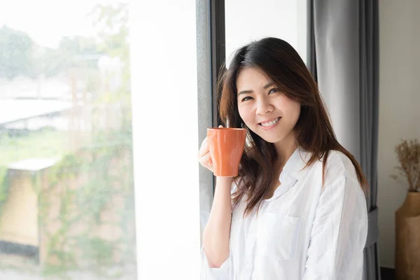 Азиатка улыбается, когда пьет кофе по утрам — стоковое фото