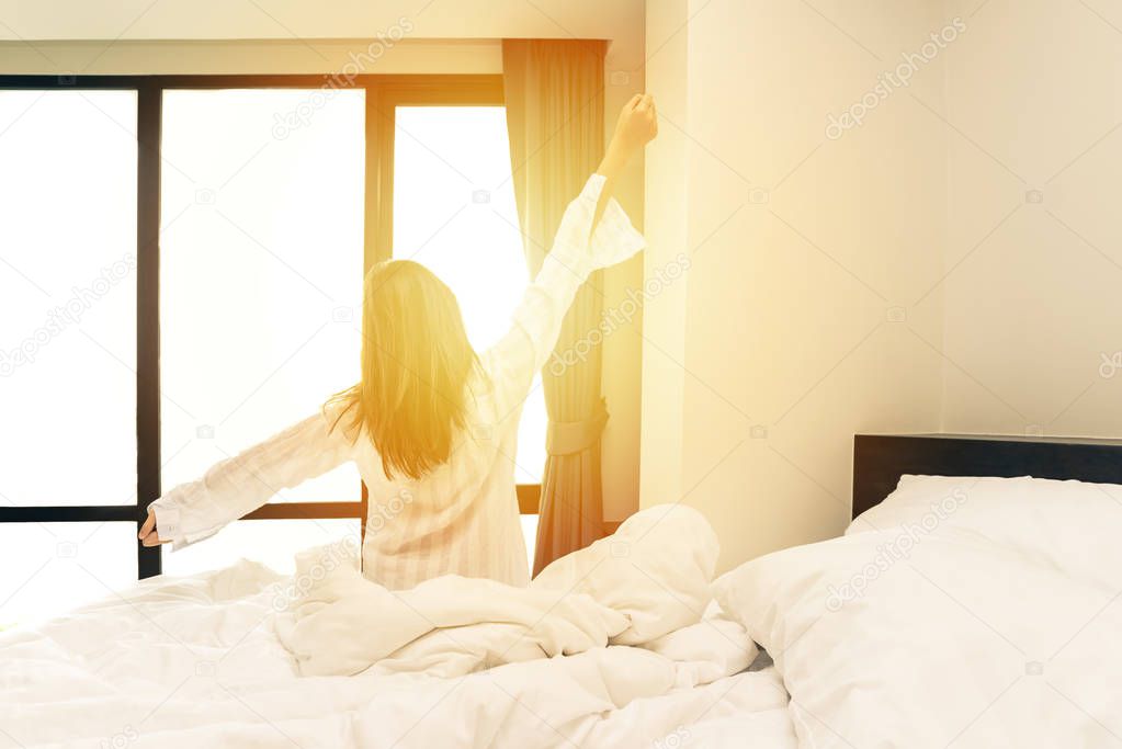 Rear view of woman stretching in bed after wake up