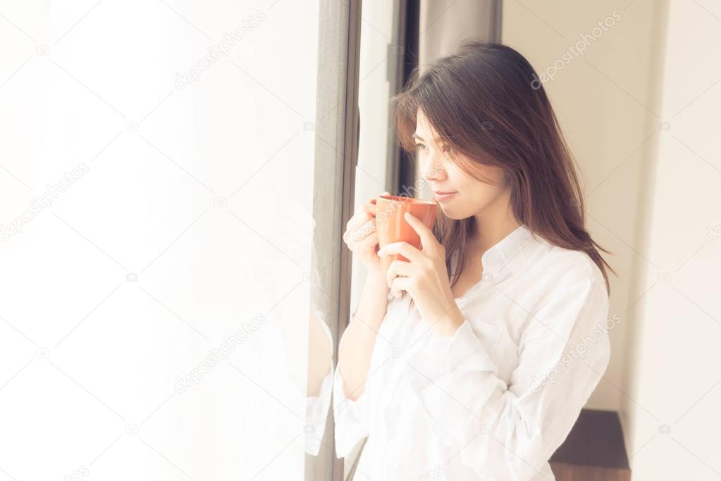 Asian woman smile while drinking coffee in morning