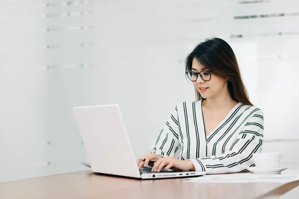 Ung asiatisk kvinna leende medan du arbetar med laptop — Stockfoto