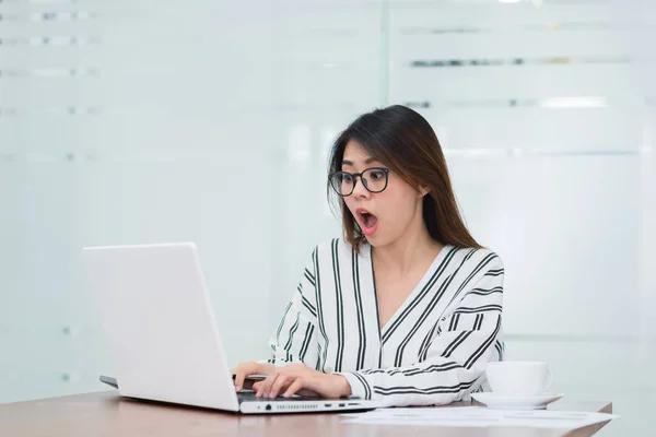 Joven mujer asiática sorprendida y emocionada mientras trabajaba con el ordenador portátil — Foto de Stock