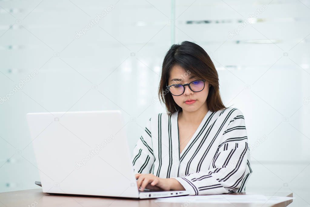 Young Asian woman smile while working with laptop