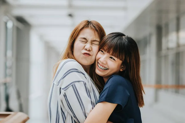 Две красивые счастливые азиатские подружки смеются и обнимаются — стоковое фото
