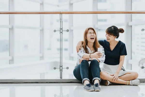 亚洲女孩最好的朋友笑和微笑时玩智能手机 — 图库照片