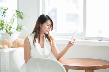 Asyalı kadın akıllı telefon kullanırken gülümseyen