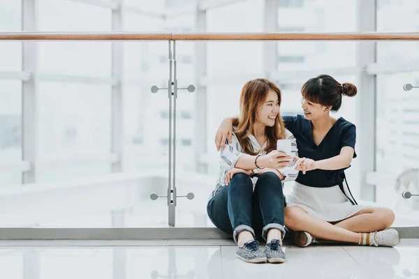 亚洲女孩最好的朋友笑和微笑时玩智能手机 — 图库照片