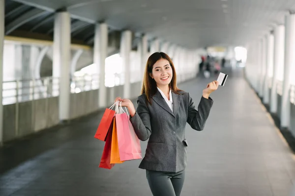Ασιατικές επιχειρηματίας εμφάνιση πιστωτική κάρτα ενώ κρατάτε την τσάντα για ψώνια — Φωτογραφία Αρχείου