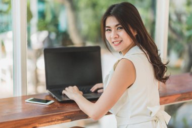 Asyalı kadın gülümseme ile laptop ile çalışırken