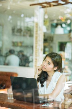 Asyalı kadın ile dizüstü bilgisayar çalışırken düşünme