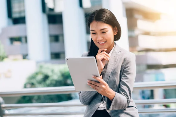 Asiatiska affärskvinna leende medan du tittar i digital tablett — Stockfoto