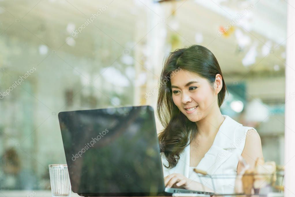  Asian woman smile while working with laptop 