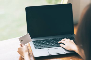  kredi kartı tutan ve online iş için dizüstü bilgisayar kullanarak el.