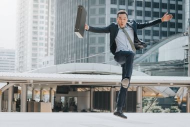 Başarı kutluyor. Mutlu heyecanlı genç Asyalı işadamı yere atlama