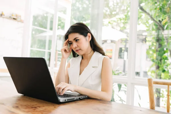 Asiatisk kvinna tänkande medan du arbetar med laptop — Stockfoto