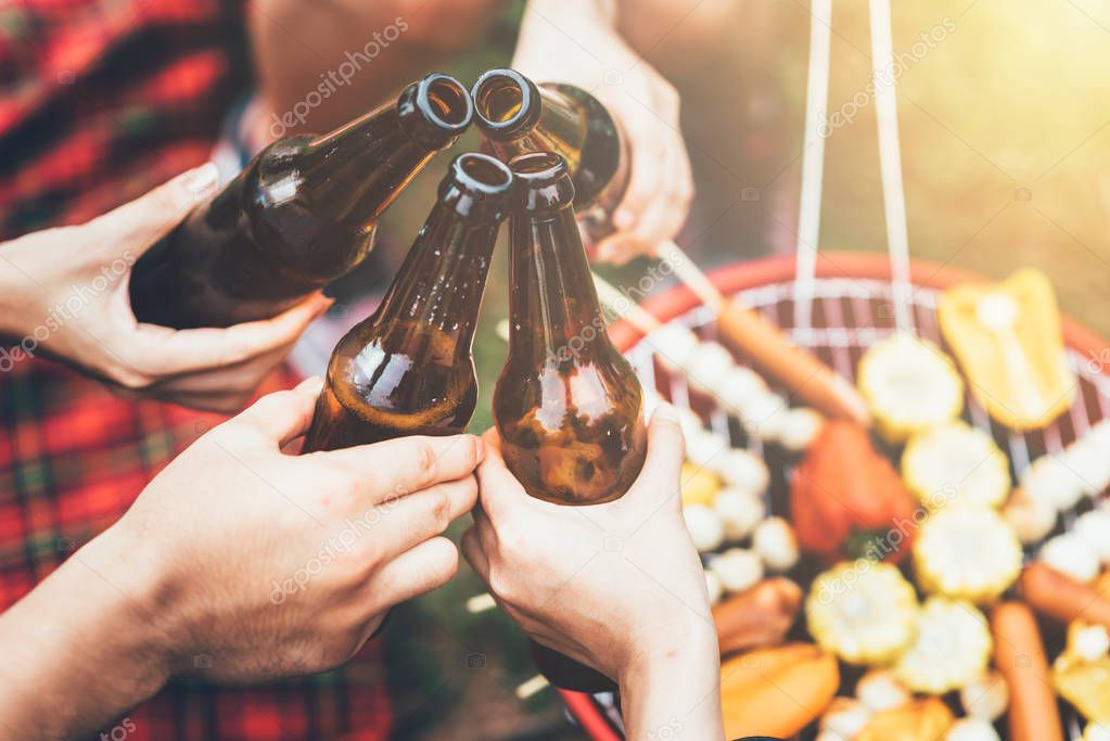 Friends clinking bottle of beer during camping party