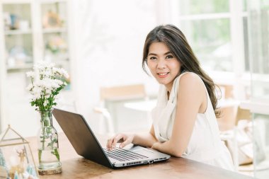 güzel genç coonfident Asyalı kadın gülümseme ile dizüstü bilgisayar çalışırken 