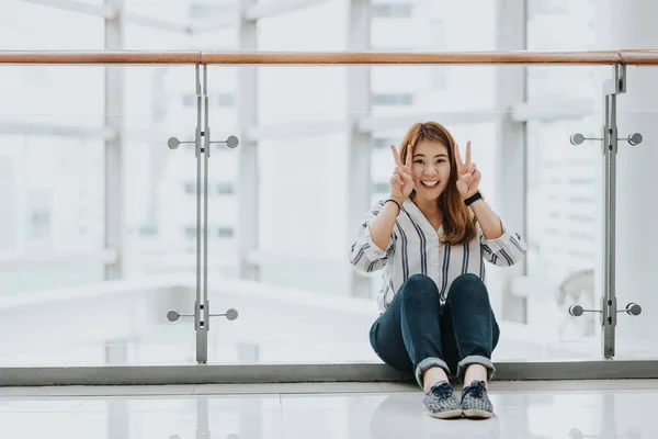 Молодые счастливые азиатские девушки смеются и улыбаются, делая знак победы — стоковое фото