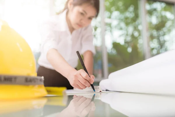 Female engineer hand drawing blueprint on table