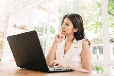 Asyalı kadın ile dizüstü bilgisayar çalışırken düşünme 