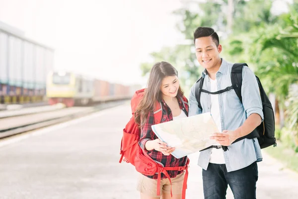 Feliz pareja asiática viajero sosteniendo un mapa en la estación de tren — Foto de Stock