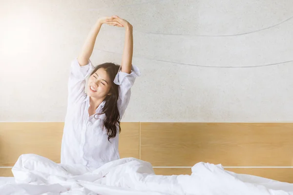 Mulher asiática esticando na cama depois de acordar de manhã — Fotografia de Stock