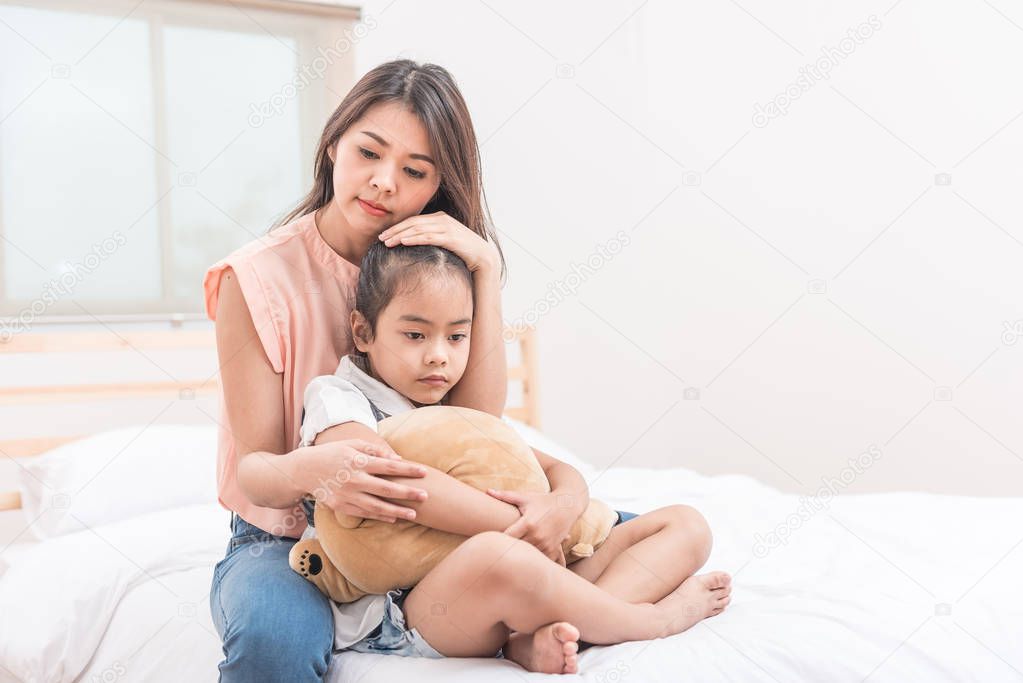 Asian mother hugging and comforting her sad daughter