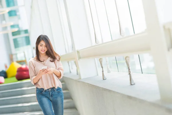 Mulher asiática usando smartphone enquanto caminha — Fotografia de Stock