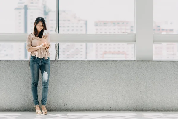Азіатський жінка за допомогою смартфона в сучасні Офісні будівлі — стокове фото