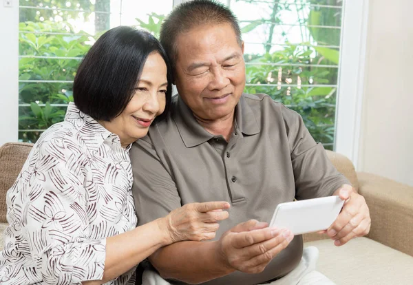 Happy senior Asian couple smiling and using smartphone