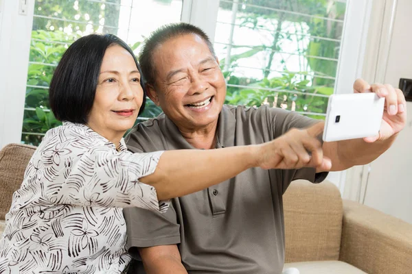 Happy senior Asian couple smiling and using smartphone