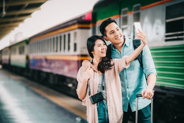 休暇旅行中に駅でスマート フォンを持つアジア ハッピートラベラー カップル撮影 Selfie — ストック写真