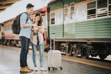 Mutlu Asya çift seyahat etmek tren istasyonunda smartphone yönde kontrol