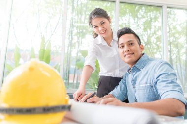 Mutlu Asain Mimarlar meslektaşım çalışma masasında plan üzerinde çalışan