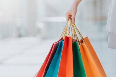 Genç kadın alışveriş merkezinde yürürken renkli alışveriş çantaları taşırken görüntüsünü kapatmak