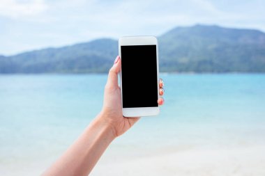 Boş ekran smartphone telefon güzel deniz ve ada arka planda tutan kadın el