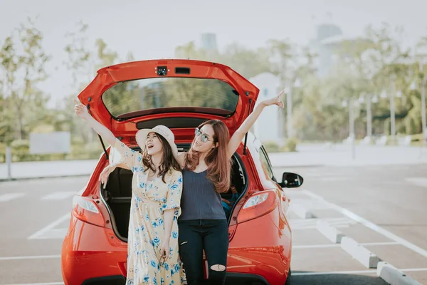 Две Счастливые Азиатки Подружки Веселятся Поднятой Рукой Сидя Багажнике — стоковое фото