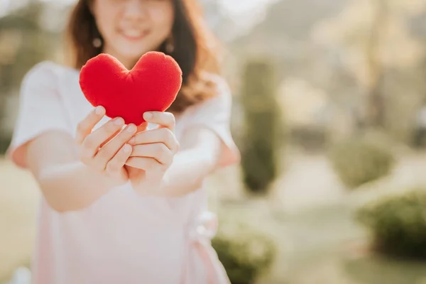 公園で屋外赤い心臓の形を保持している美しい若いアジア女性 — ストック写真