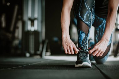 Spor salonunda daha önce eğitim onun ayakkabı bağcığı bağlama kadın görüntüsünü kırpılmış