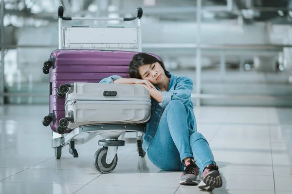Жінка спить з багажним візком в аеропорту — стокове фото