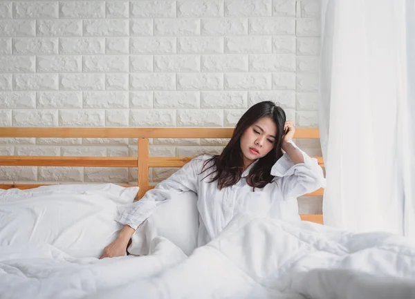 Onun yatağında hasta ve mutsuz seyir çekici genç Asyalı kadın uyan.